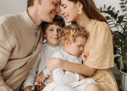A loving family of four shares a tender moment in a cozy indoor setting, embracing and smiling.